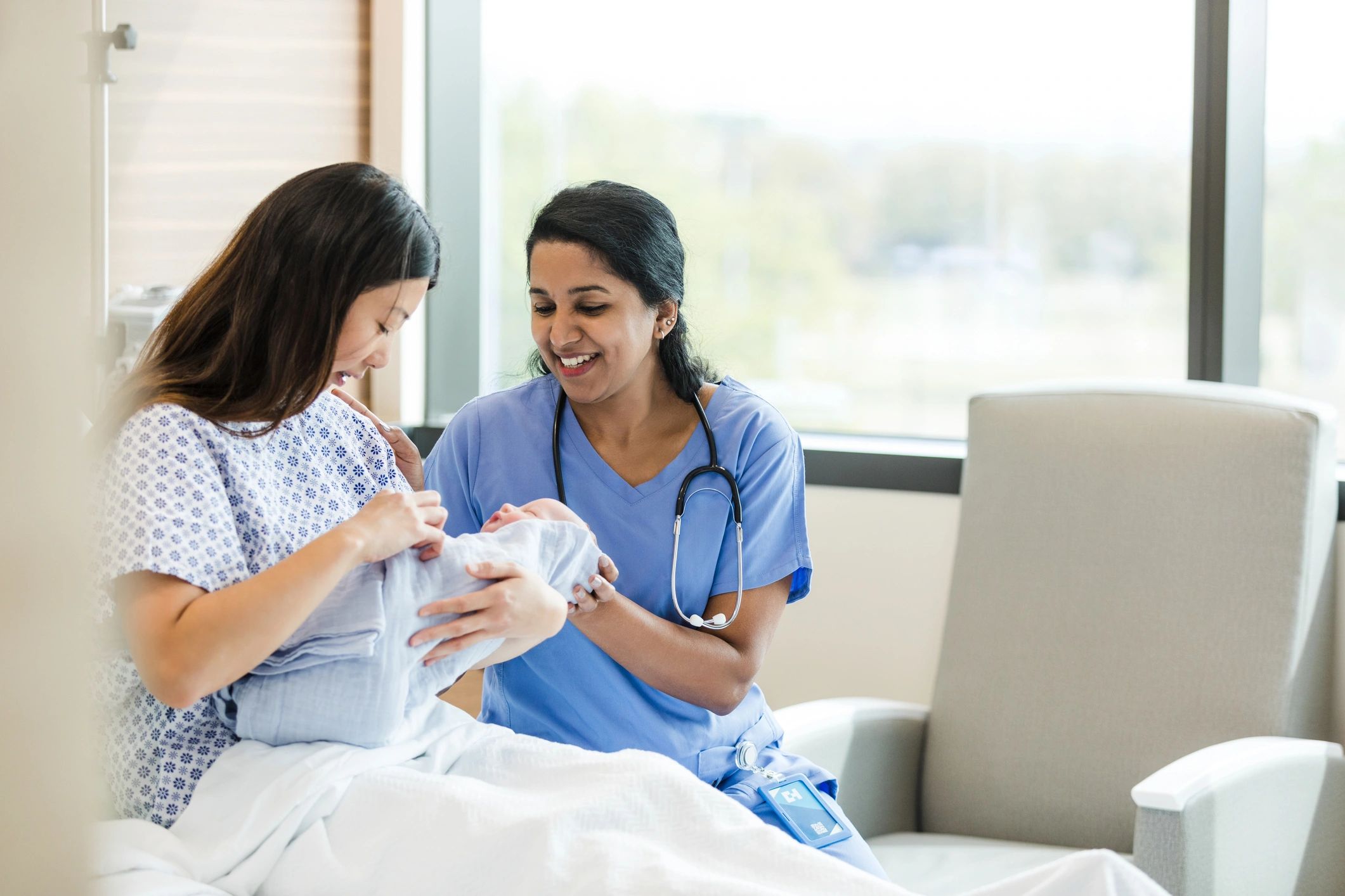 Postpartum nurse supporting a new mother with her newborn in a hospital room
