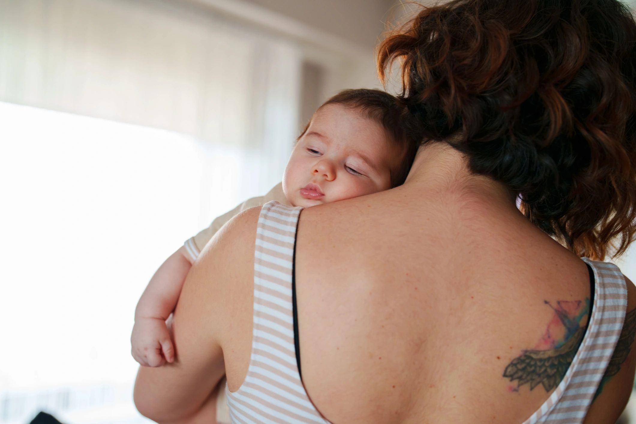 Newborn resting on a parent's shoulder at home