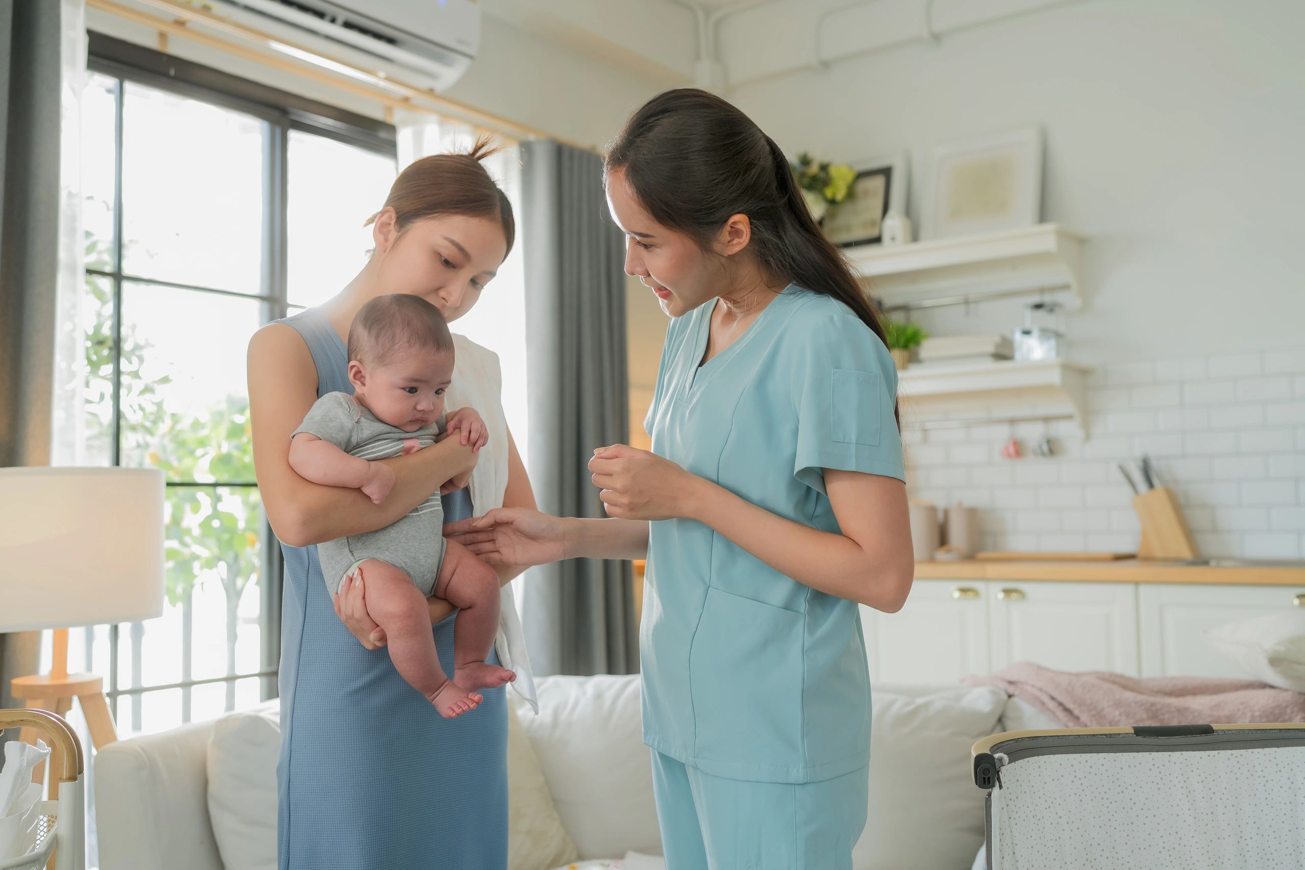 Healthcare professional examining a baby at home while mother watches