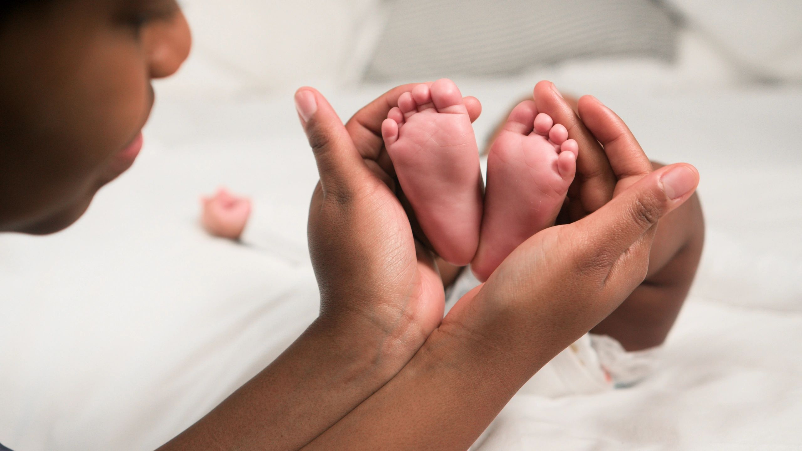 Loving Parent Gently Holding Tiny Newborn Baby Feet in Warm Hands